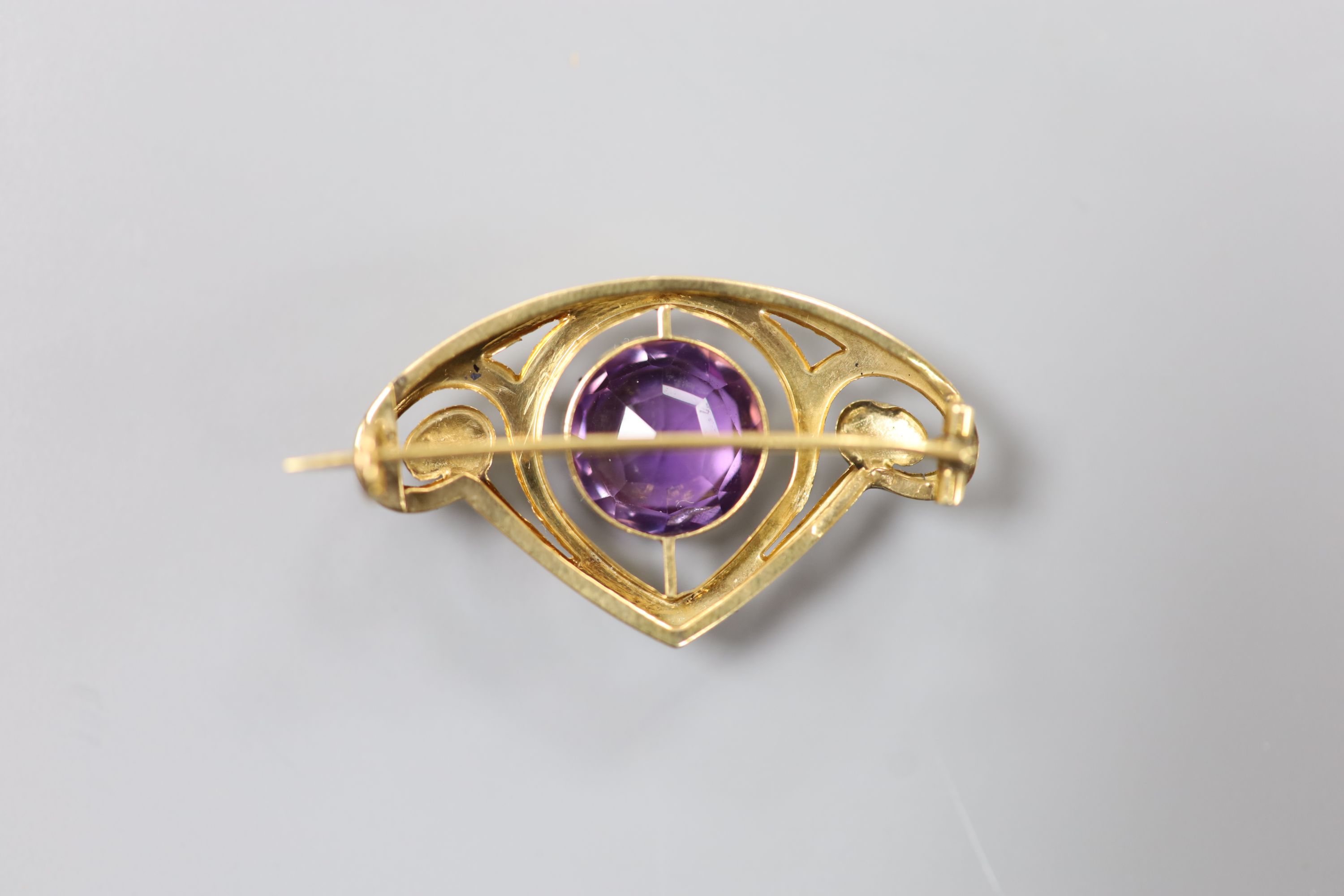 An early 20th century Art Nouveau yellow metal and amethyst set stylised brooch